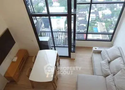 Modern living room with large windows and city view, featuring a cozy sofa and dining area.