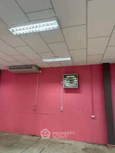 Spacious interior with vibrant pink walls and modern lighting, ideal for creative workspace or studio.