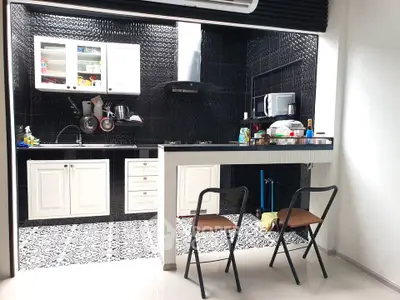 Modern kitchen with black backsplash, white cabinets, and breakfast bar with stools.