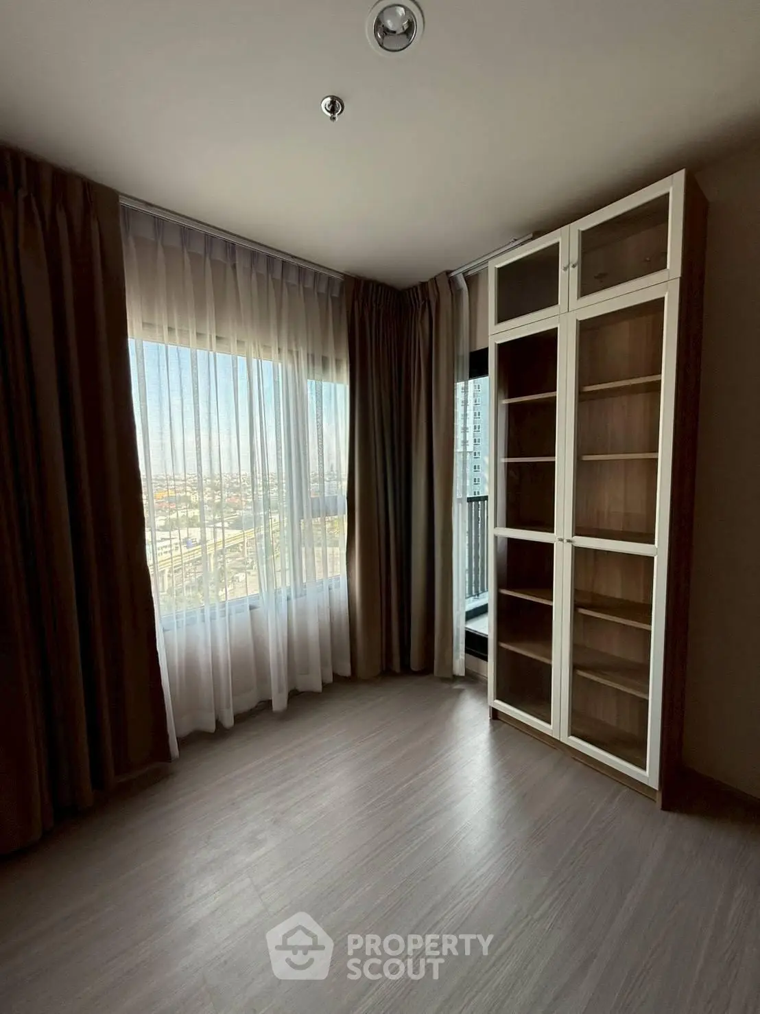 Spacious corner unit with large windows and built-in shelving, offering abundant natural light and city views.