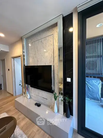 Modern living room with sleek TV setup and balcony access, featuring elegant decor and natural light.