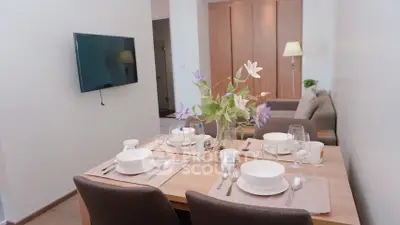 Modern dining area with elegant table setting and wall-mounted TV in cozy apartment.