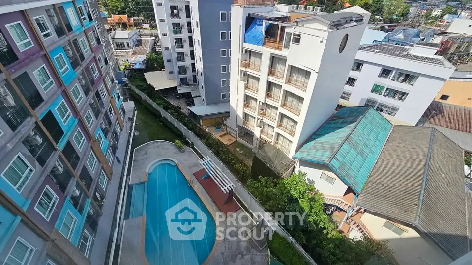Aerial view of modern apartment buildings with a swimming pool and cityscape backdrop.