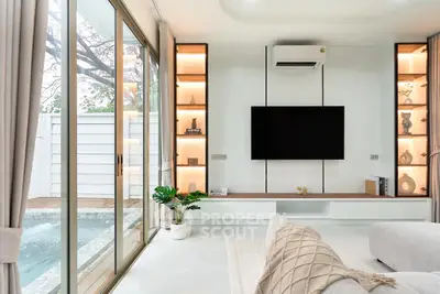 Luxurious living room with pool view, modern decor, and large TV setup