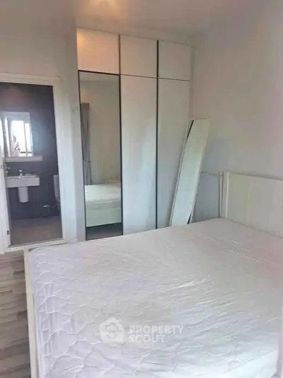 Spacious bedroom with modern wardrobe and ensuite bathroom in a stylish apartment.