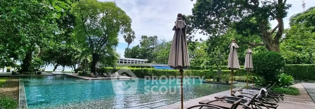Luxurious outdoor pool area with lush greenery and sun loungers, perfect for relaxation.