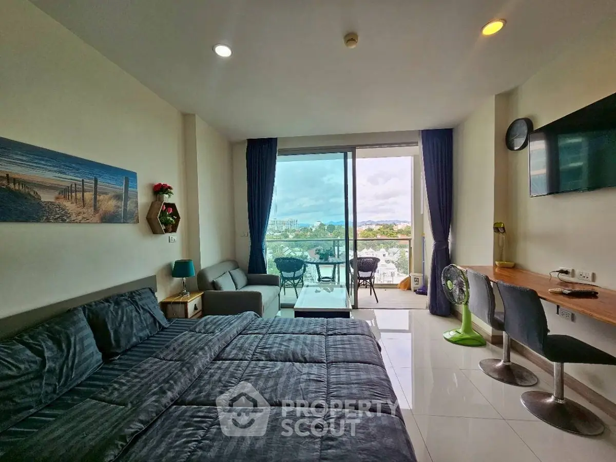 Spacious bedroom with balcony offering stunning city view, modern decor, and ample natural light.