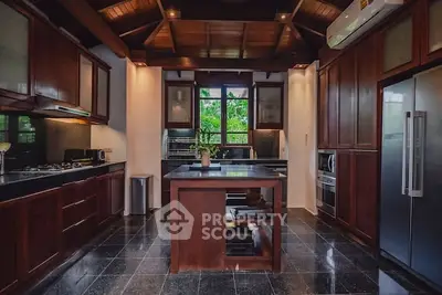 Luxurious kitchen with dark wood cabinets, island, and modern appliances in a stylish home.