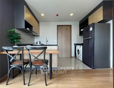 Modern kitchen with dining area, washing machine, and sleek appliances in open layout.