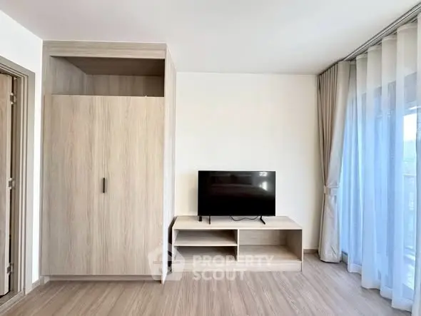 Modern living room with sleek TV stand and large window with sheer curtains