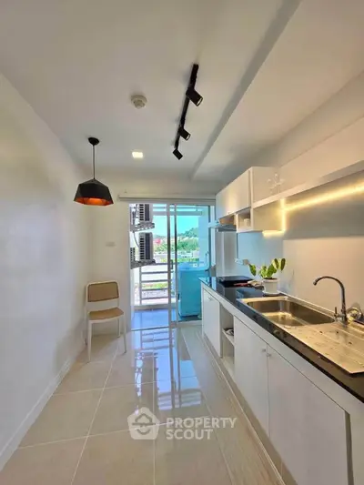 Modern kitchen with sleek design and open layout, featuring stylish lighting and outdoor view.