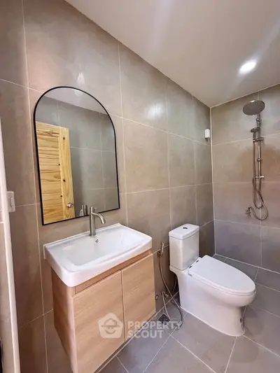 Modern bathroom with sleek fixtures and neutral tiles, featuring a stylish vanity and rainfall shower.