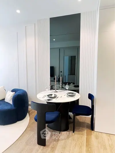 Modern living room with stylish dining area, featuring a round table and elegant blue chairs, perfect for urban living.