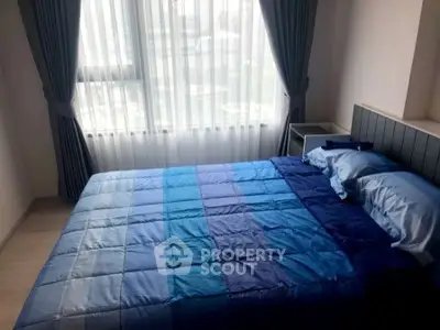 Cozy bedroom with large window and blue bedding in modern apartment