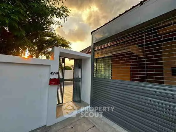 Charming modern home entrance with sleek gate and warm sunset lighting.