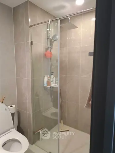 Modern bathroom with glass shower enclosure and sleek tile design.