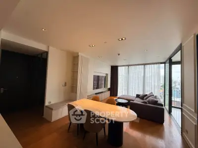 Spacious modern living room with large windows and city view, featuring elegant furniture and wooden flooring.