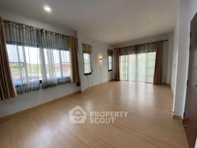 Spacious empty room with large windows and wooden flooring, perfect for customization.