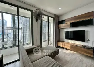 Modern living room with large windows and city view, featuring stylish furniture and wall-mounted TV.