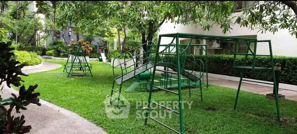 Charming garden area with playground equipment in a residential complex, perfect for family living.