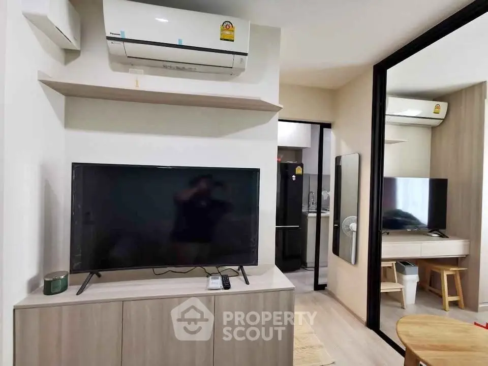 Modern living room with air conditioning and sleek TV setup in a cozy apartment.