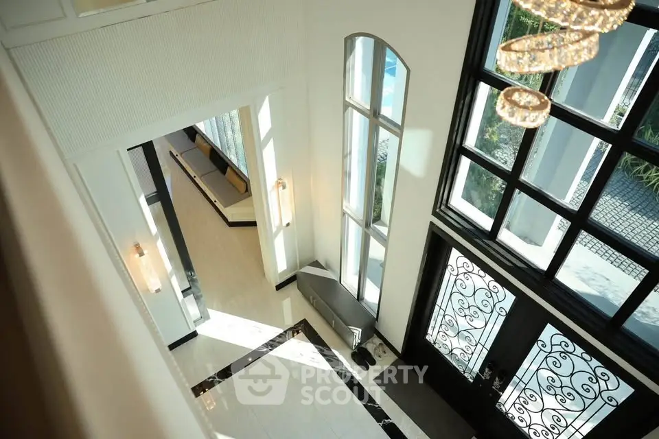Luxurious high-ceiling entrance with elegant chandelier and large windows