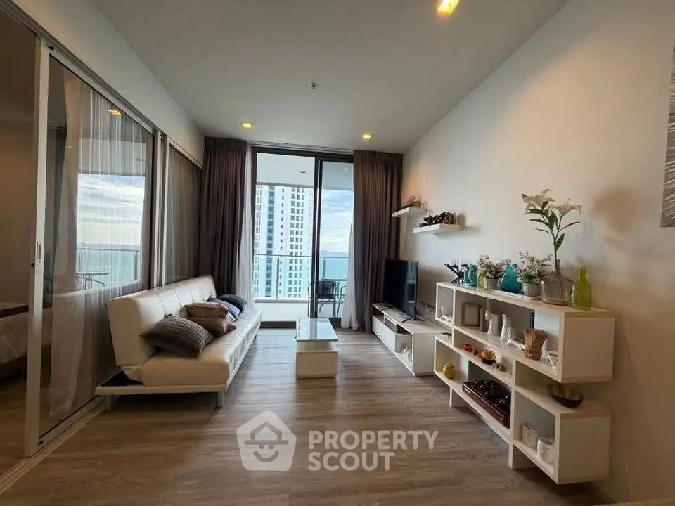 Modern living room with ocean view, stylish decor, and spacious balcony access in luxury apartment.