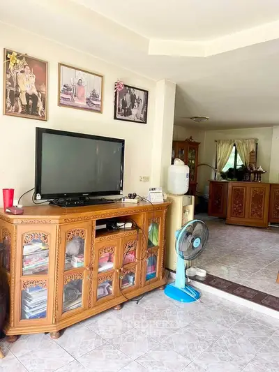 Charming living room with traditional wooden furniture and tiled flooring, perfect for cozy family gatherings.