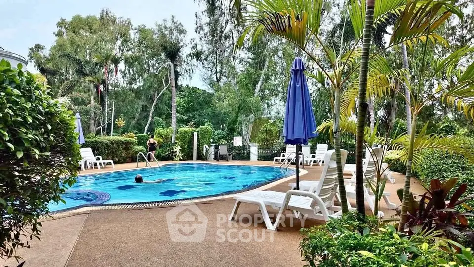 Luxurious outdoor pool area with lush greenery and sun loungers, perfect for relaxation.
