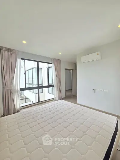 Spacious bedroom with large windows and modern air conditioning unit