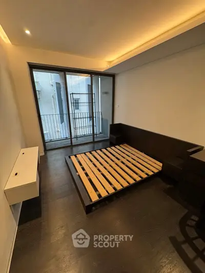 Modern bedroom with sleek dark flooring and large glass doors leading to a balcony.