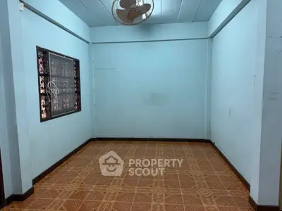 Spacious empty room with tiled floor and ceiling fan, ideal for customization.