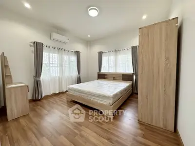 Spacious bedroom with wooden flooring and large windows for natural light