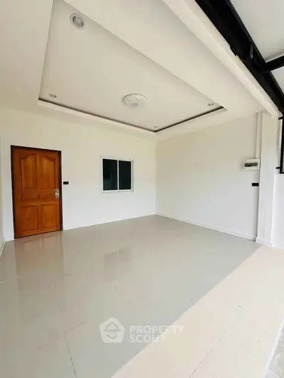 Spacious empty room with tiled floor and wooden door, ideal for customization.
