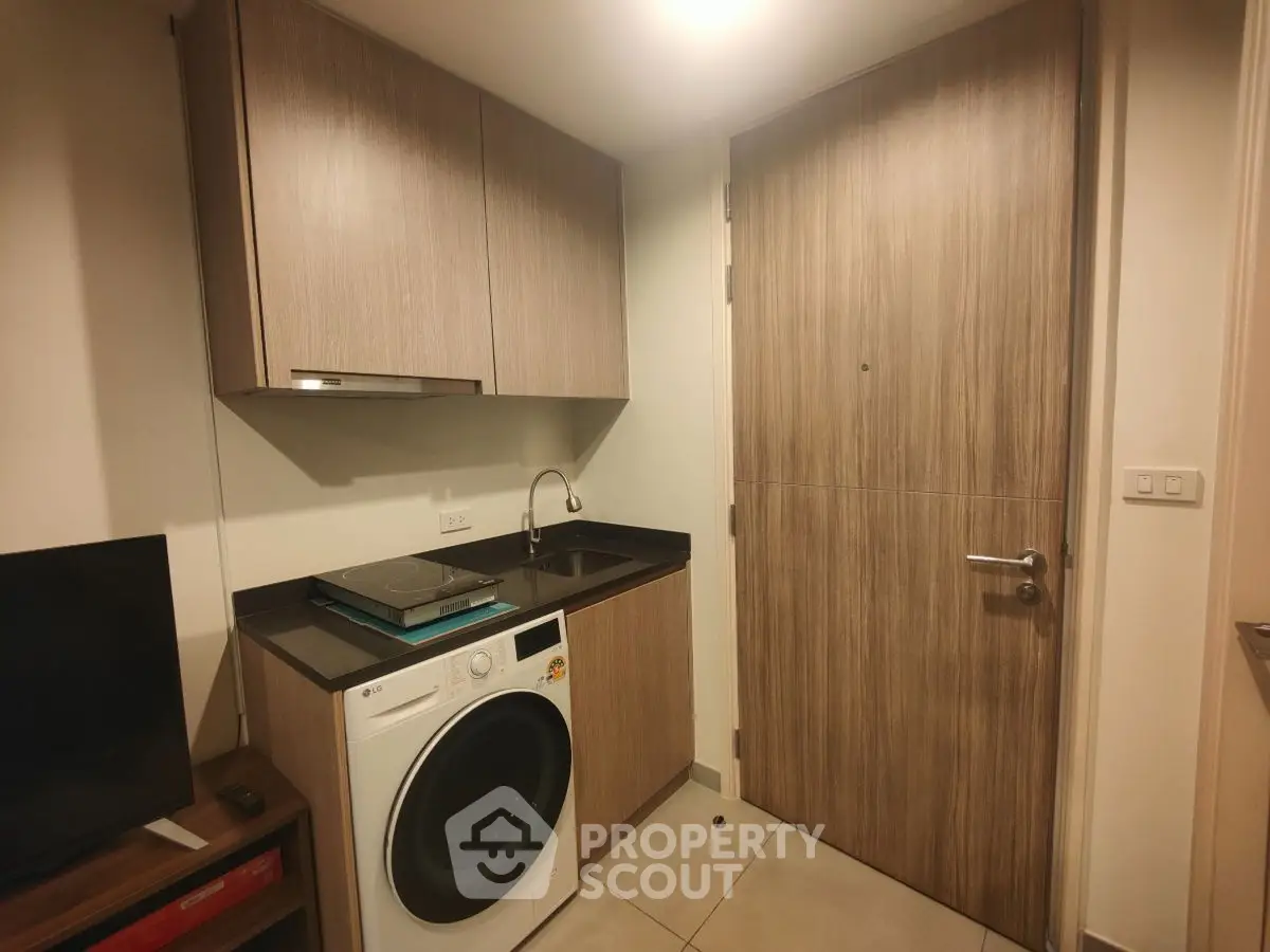 Compact laundry area with modern washing machine and wooden cabinetry in a cozy apartment.