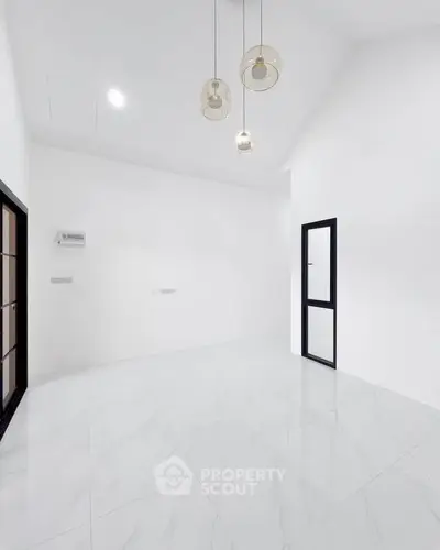 Spacious modern room with high ceiling and elegant pendant lights, perfect for versatile living space.