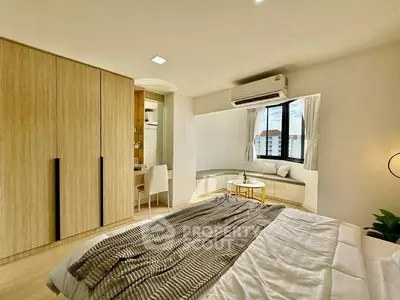 Spacious bedroom with modern decor and large window offering city views.