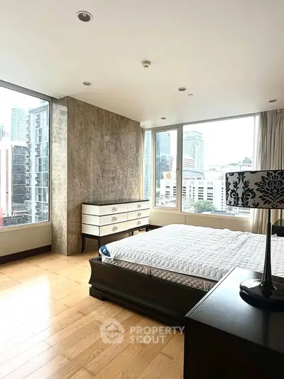 Spacious bedroom with city view, featuring elegant furniture and large windows for natural light.