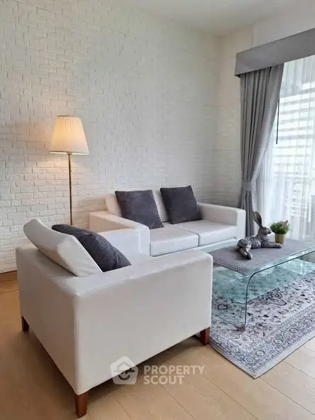 Elegant living room with white brick wall, cozy sofa, and glass coffee table in modern apartment.