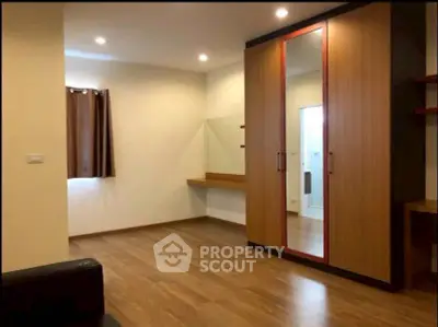 Spacious bedroom with wooden flooring and large wardrobe, perfect for modern living.