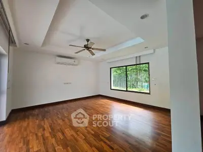 Spacious living room with wooden flooring and large window offering natural light.