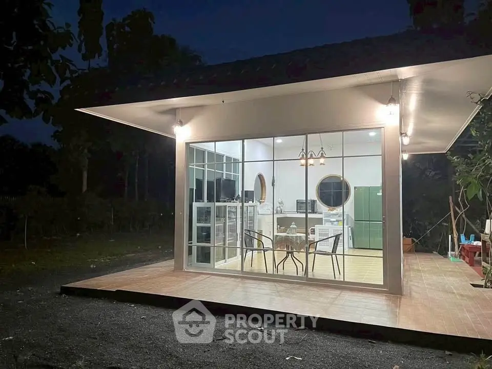 Charming modern house with large glass windows and cozy patio at dusk.