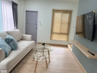 Modern living room with cozy sofa, glass coffee table, and wall-mounted TV, perfect for relaxation.