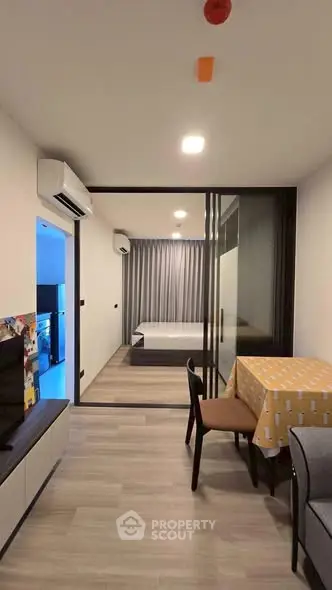 Modern apartment interior with open layout, featuring a cozy living area and bedroom separated by glass doors.