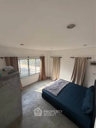 Spacious bedroom with large windows and minimalist decor, offering abundant natural light and serene ambiance.