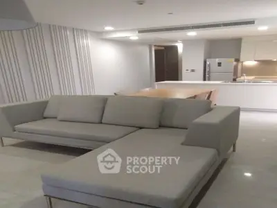 Modern living room with sleek sofa and open kitchen layout in stylish apartment.