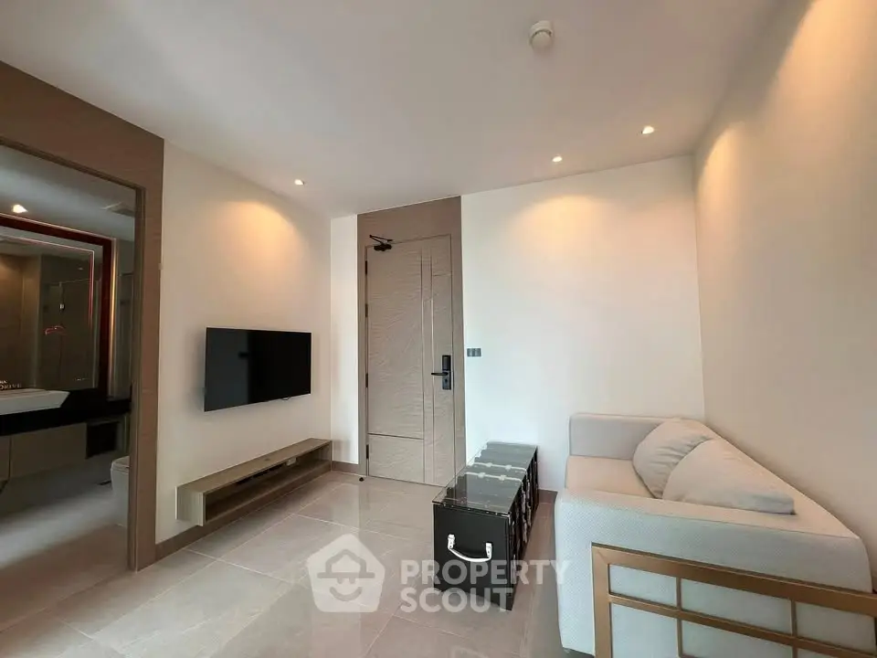 Modern living room with sleek design and neutral tones, featuring a wall-mounted TV and stylish furniture.