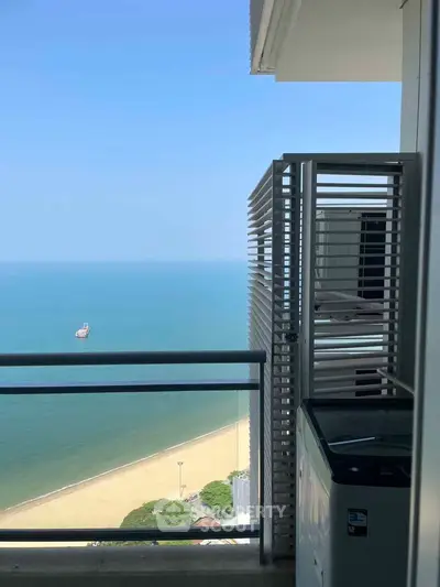 Stunning ocean view from a high-rise balcony with serene beach and clear blue sky.
