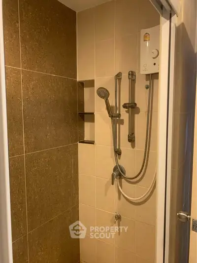 Modern shower area with sleek fixtures and tiled walls in a cozy bathroom.