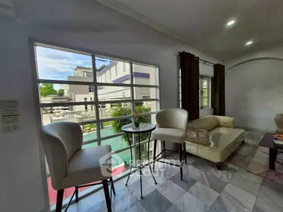 Spacious living room with large windows and elegant furniture overlooking a serene neighborhood view.